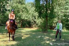 Uczestniczka wakacyjnej szkółki jeździeckiej na koniu z instruktorką podczas jazdy na lonży