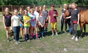Grupa uczestników Wakacyjnej szkółki jeździeckiej wraz z instruktorkami i koniem